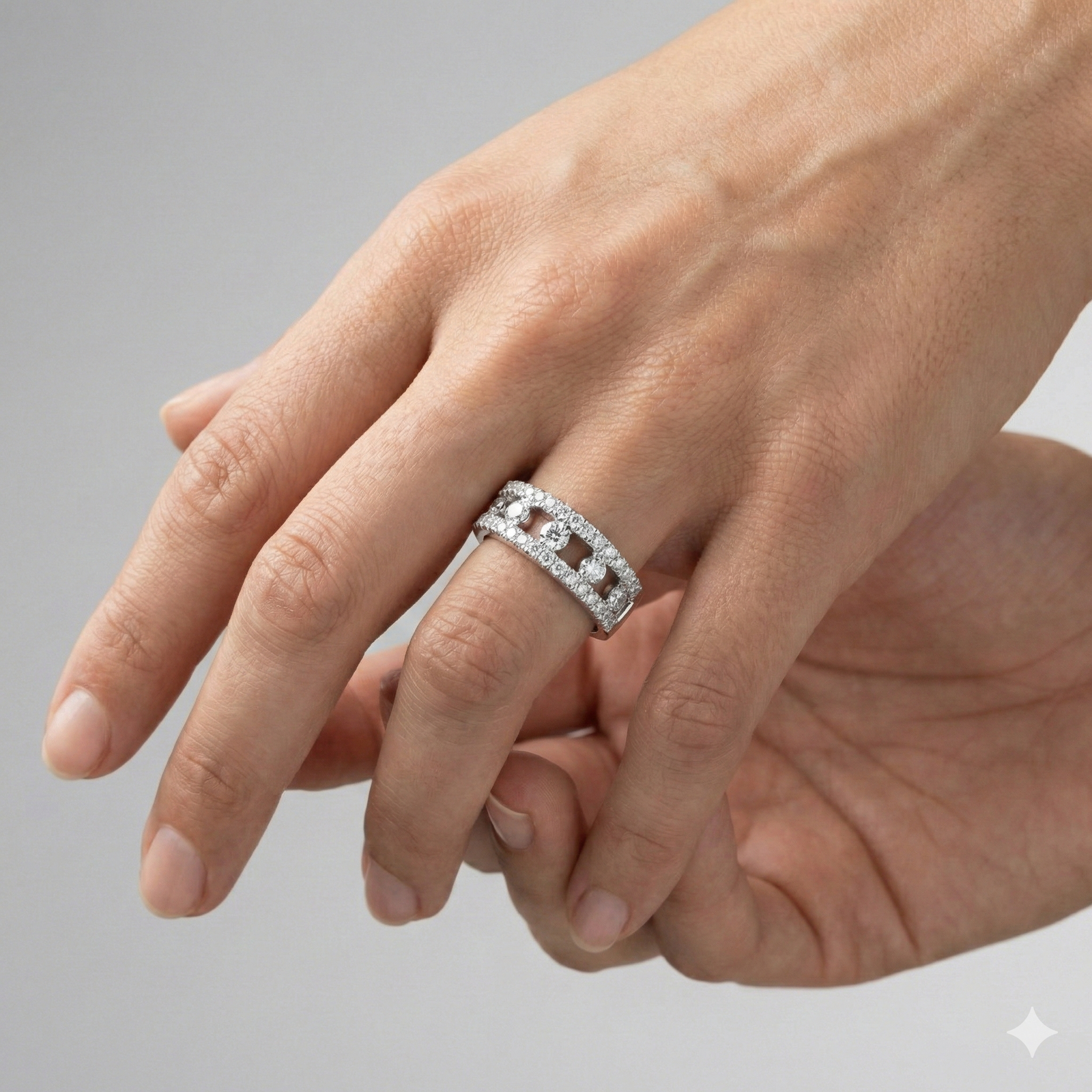 A top-down view of a 14K white gold wide band ring with three rows of pavé diamonds on hand.
