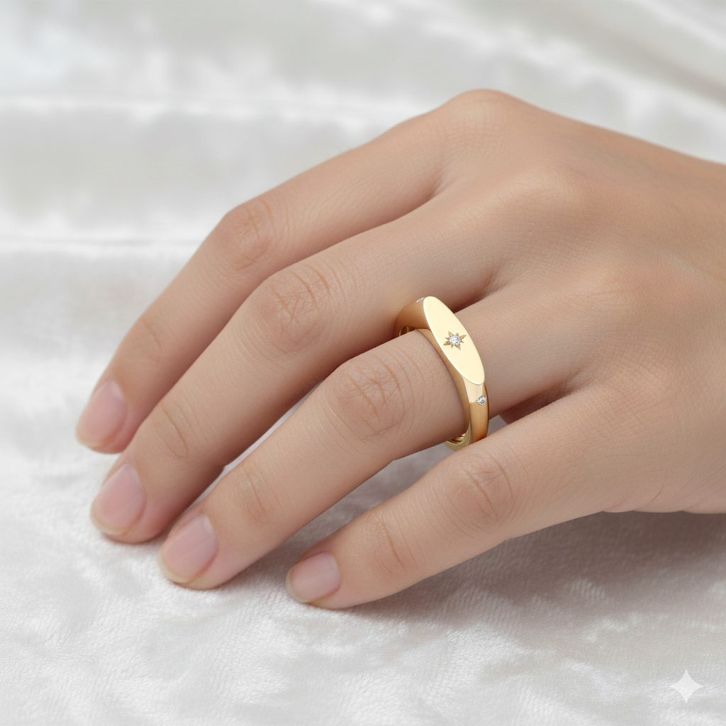 An angled view of a 14K yellow gold signet ring, showcasing the central jewel and the sunburst design on a finger.