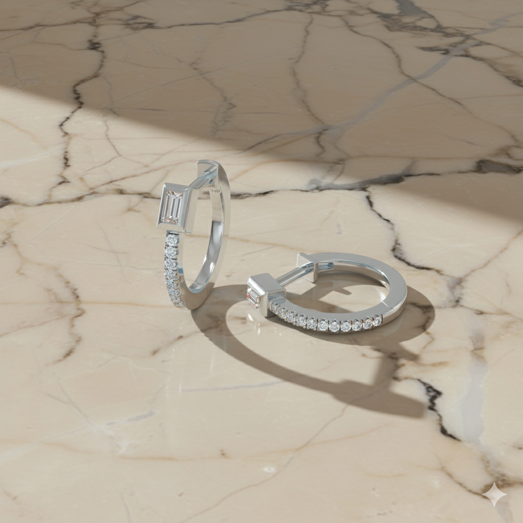Displayed against a marble background, the 14K white gold huggie hoops feature pavé and baguette diamonds.