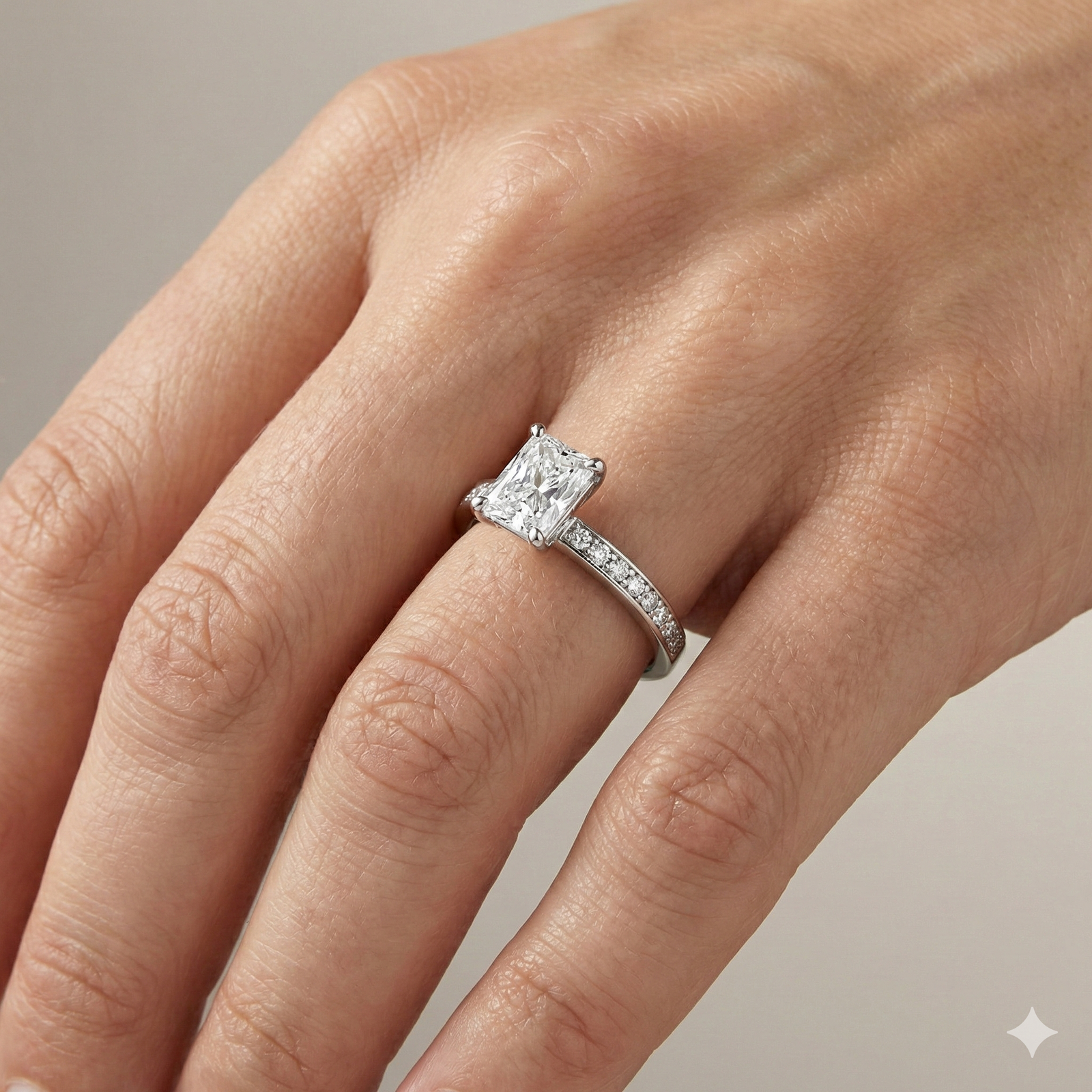 Radiant cut diamond engagement ring in 14k white gold with a diamond channel band and cathedral setting on a hand