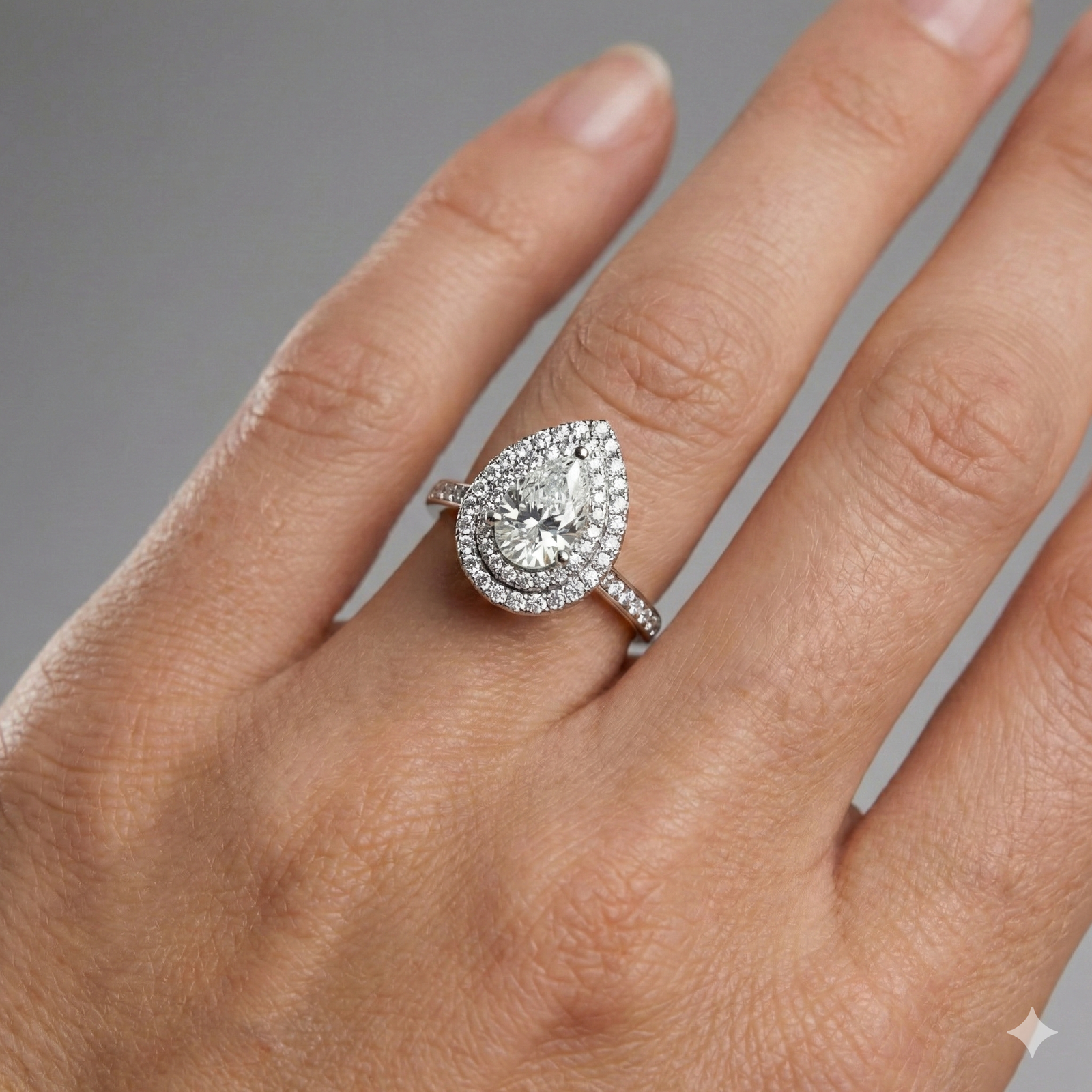 Pear cut diamond engagement ring in 14k white gold with a diamond channel band and cathedral setting on a hand
