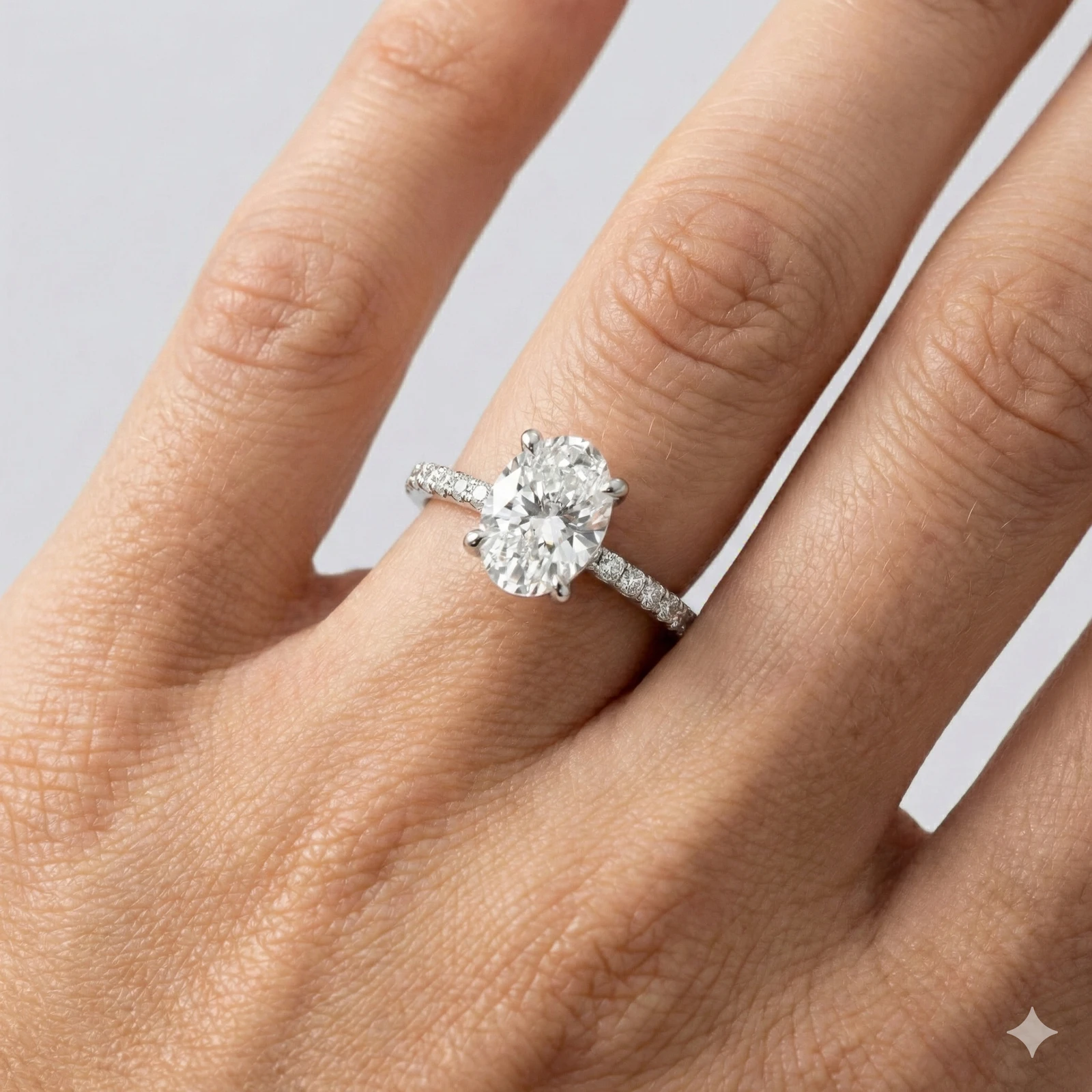 Oval cut diamond engagement ring in 14k white gold with a prong diamond band and cathedral setting on a hand
