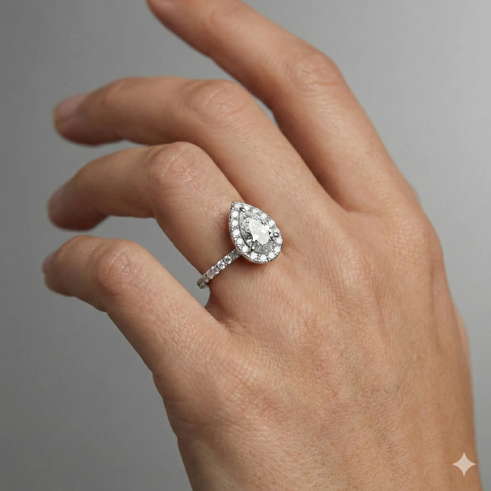 Pear cut diamond engagement ring in 14k white gold with a prong diamond band and cathedral setting on a hand