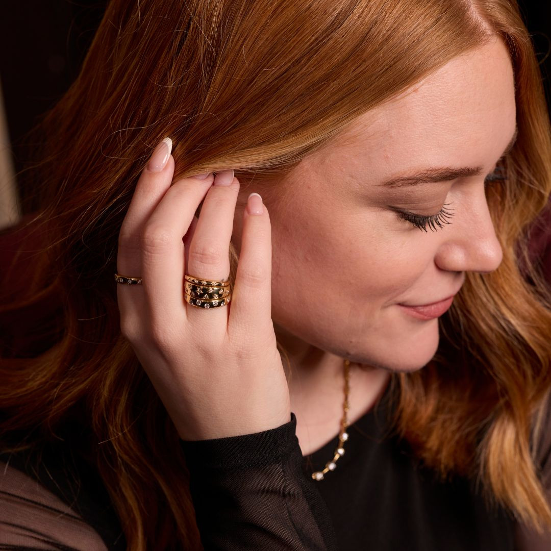 A high-polish, slender 14K yellow gold stackable ring by Amorati, delicately detailed with petite star-shaped insets, each set with a shimmering round lab-grown diamond, elegantly displayed on a model’s hand. Amorati’s signature F O U R T E E N T H Collection.