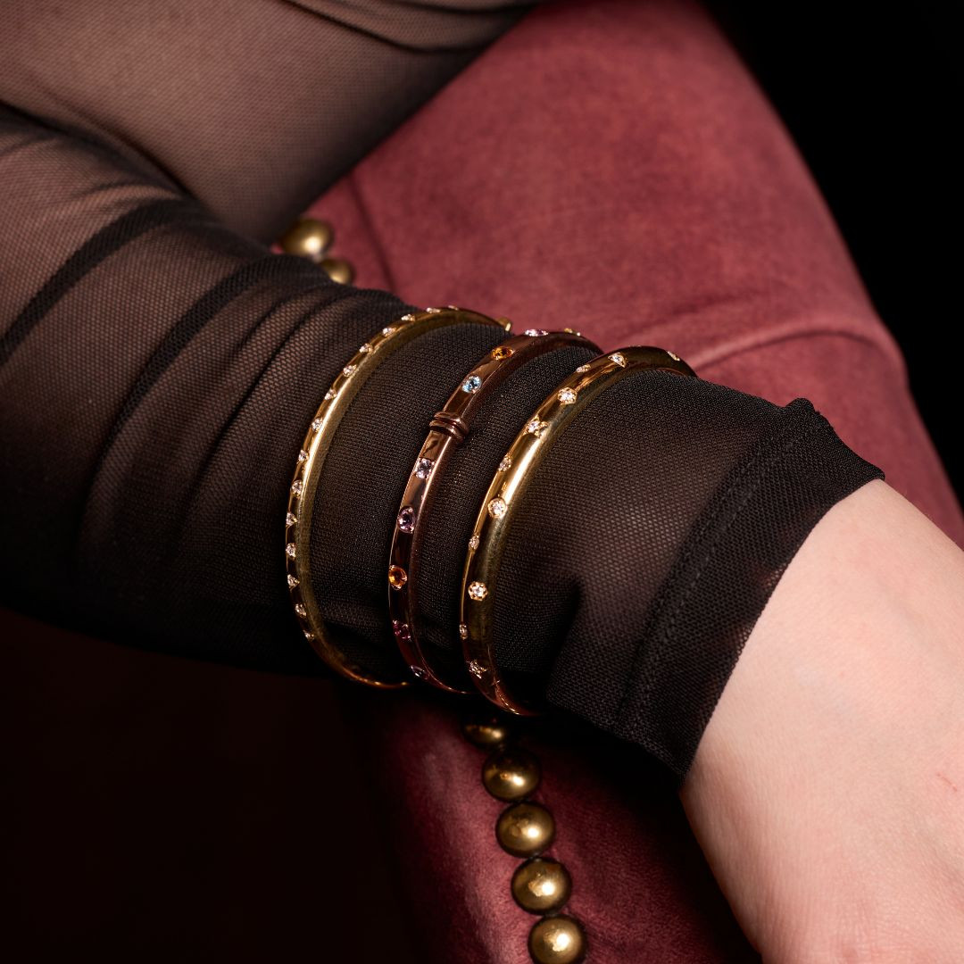 A luminous, high-polish 14K yellow gold bangle from the Amorati Fourteen Collection, featuring delicately scattered star-shaped insets set with shimmering round lab-grown diamonds, gracefully styled on a model’s wrist.