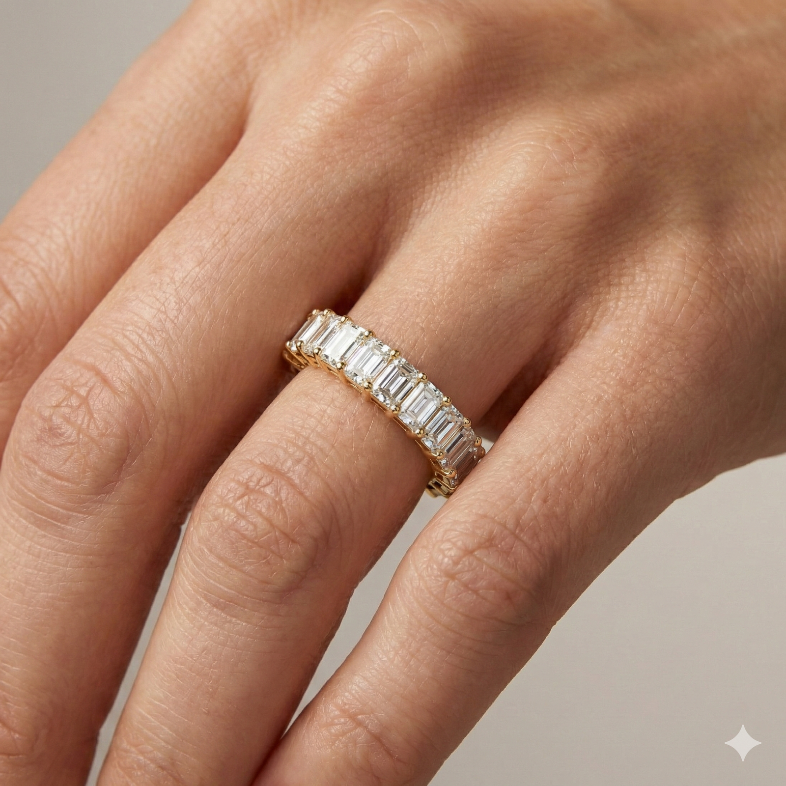 A breathtaking 14k yellow gold full eternity band featuring a continuous circle of 2.3 total carats of shimmering emerald-cut lab-grown diamonds on hand.