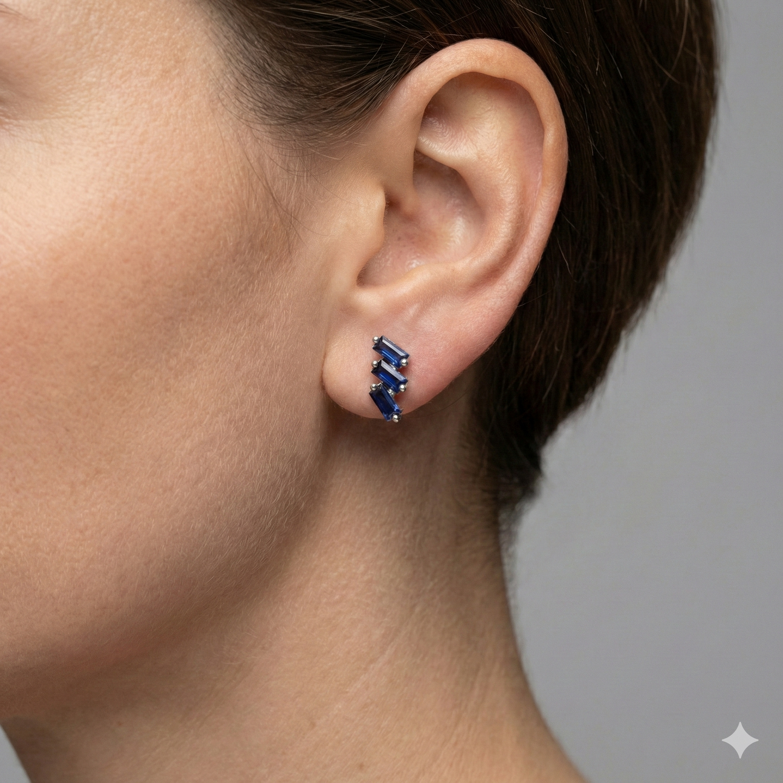 A close-up, profile shot of a person’s ear and jawline, showcasing the Cascading Baguette-Cut Stud Earrings. The model’s hair is swept back, allowing the jewelry to take center stage against a soft-focus, neutral background.