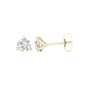 An angled view of a pair of 14K yellow gold three-prong diamond stud earrings, showcasing the full design.