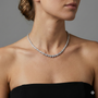 White gold diamond tennis necklace worn on the figure, sitting smoothly along the neckline and showcasing uniform diamond brilliance with a refined silhouette.