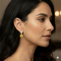 A model wearing the gold drop earrings, showcasing the elegant scale of the white and yellow diamond flower design.