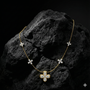 Yellow gold floral diamond necklace resting on a textured dark rock, highlighting the organic flower design, diamond brilliance, and contrast against a rugged natural surface.