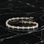 White gold oval diamond tennis bracelet styled on black marble, emphasizing contrast, diamond brilliance, and luxury finish.