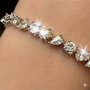 On figure view of oval, pear & round multi shape diamond tennis bracelet.