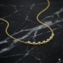Lifestyle view of a yellow gold diamond station necklace worn on the neck, showcasing evenly spaced round white diamonds on a delicate chain.