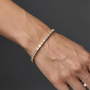 Lifestyle view of a yellow gold diamond tennis bracelet worn on the wrist, showcasing emerald cut diamonds in a refined fine jewelry design.