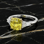 Angled view of a white gold ring featuring a yellow diamond center and white diamond side stones resting on a black marble surface.