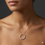 Lifestyle view of a yellow gold circle pendant necklace worn on the neck, showcasing pavé white diamonds on a delicate chain.