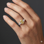 Lifestyle view of a white gold three-stone ring worn on the hand, showcasing a yellow diamond center with pear-shaped white diamond accents.