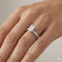 Emerald cut diamond engagement ring in 14k white gold with a diamond channel band and cathedral setting on a hand