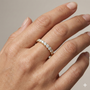 A dainty 14k yellow gold wedding band featuring 0.50 total carats of round-cut lab-grown diamonds in a classic half eternity setting on hand.
