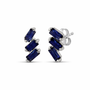 A pair of cascading stud earrings featuring a vertical arrangement of three baguette-cut blue sapphires. The rectangular gemstones are staggered in a step-like formation and held in a minimalist 18k yellow gold setting, shown against a clean, white studio background.