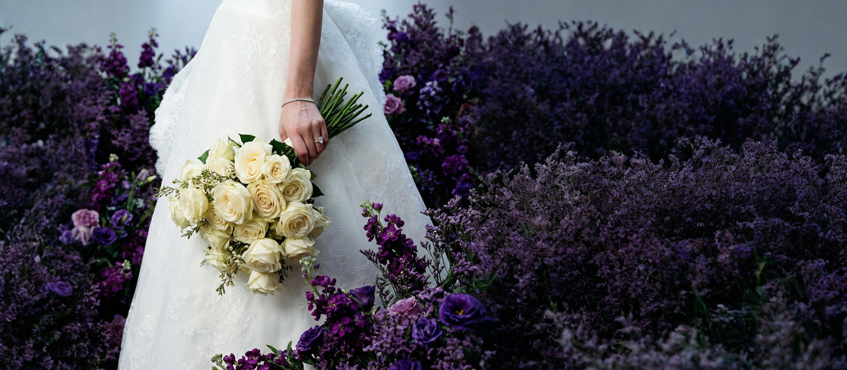 Bride holding white roses surrounded by lavender fields, wearing a lab-grown diamond ring by Amorati