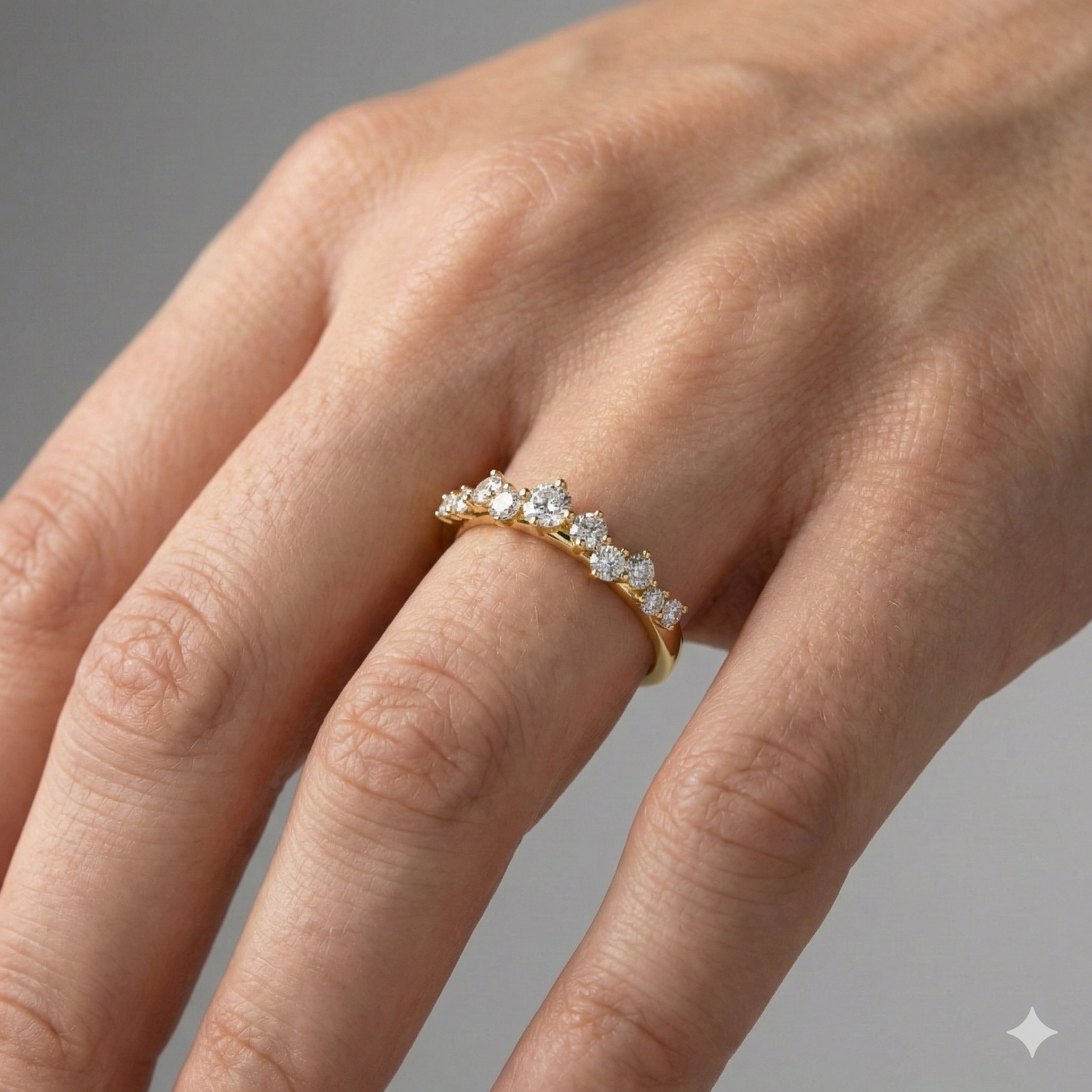 A top-down view of a 14K yellow gold ring with a five-stone cluster of alternating marquise and round diamonds on hand.