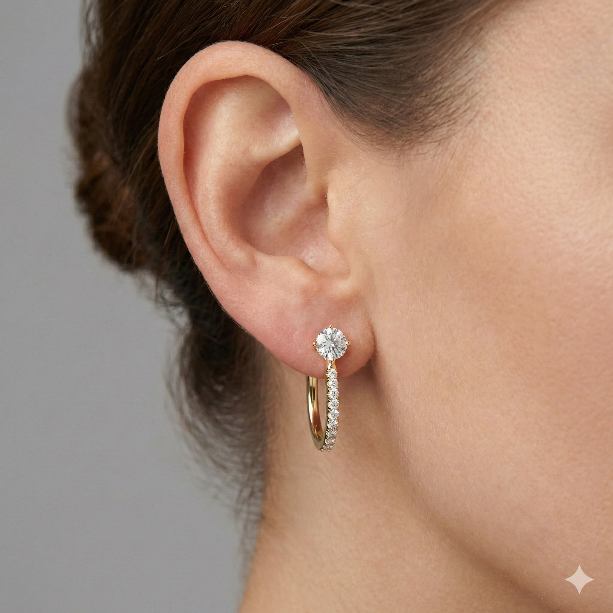 A pair of 14K yellow gold huggie hoops, shown from the front with a single diamond at the top and a pavé diamond drop on ear.
