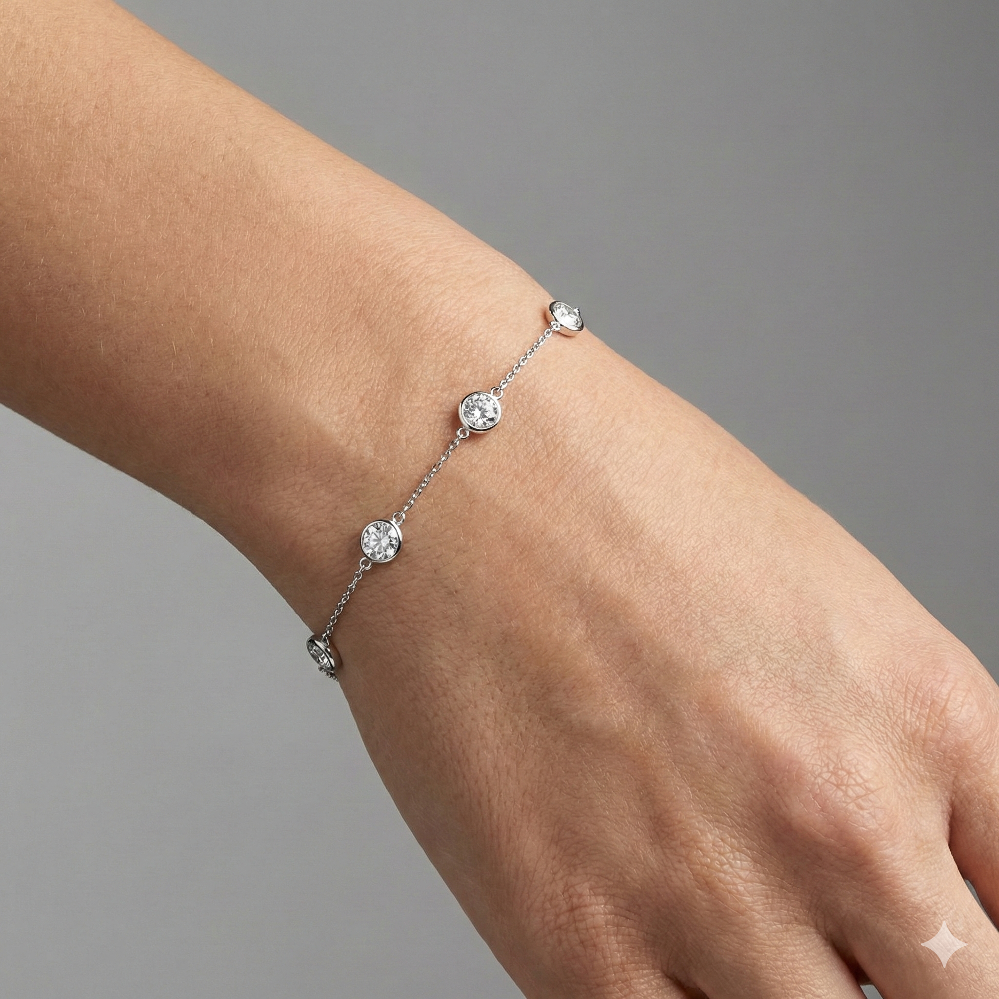 A full top-down view of a 14K white gold bracelet, showing the spaced-out, bezel-set diamonds on the delicate chain on figure.