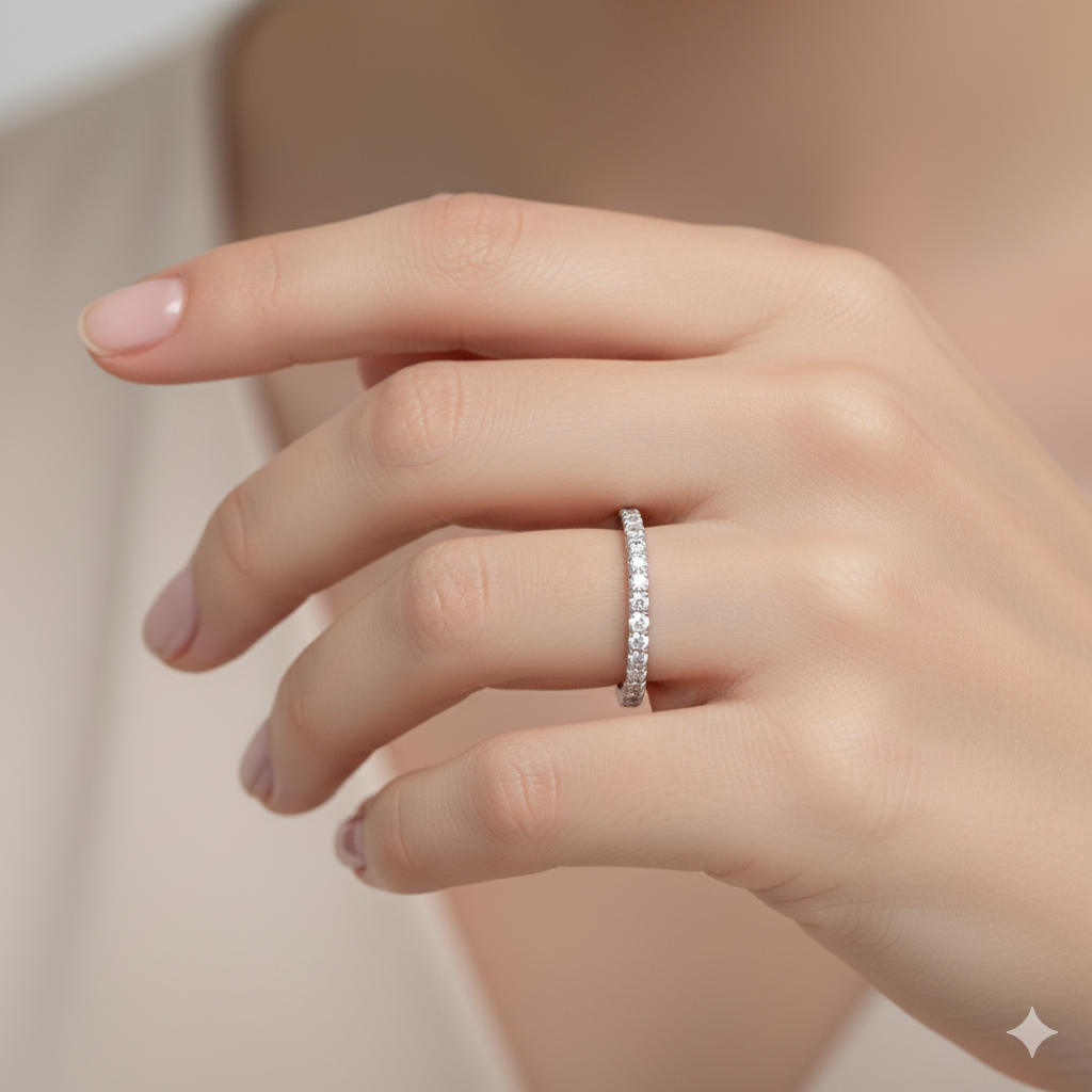 A top-down view of a 14K white gold thin band ring with a continuous line of petite, pavé-set round jewels on a finger of a hand.