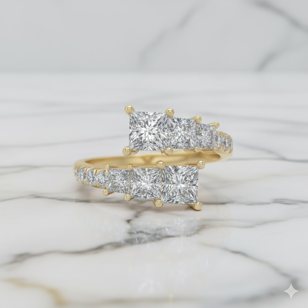 A top-down view of a 14K yellow gold ring with an asymmetrical cluster of princess-cut and baguette diamonds set on marble.