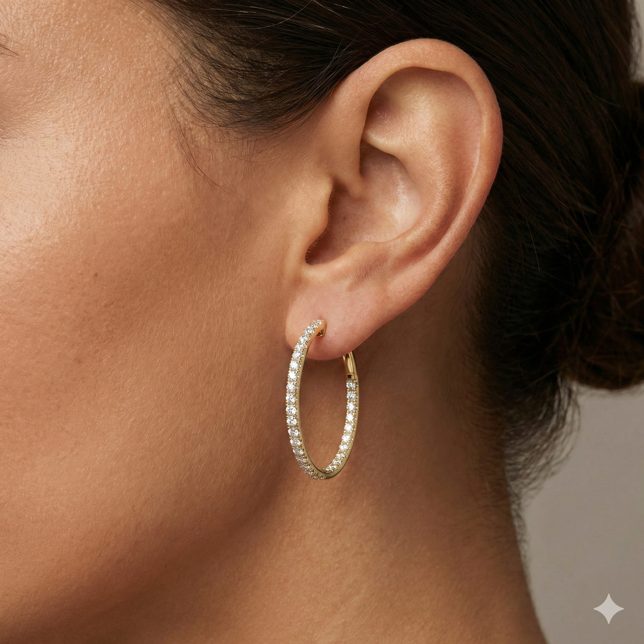 A pair of 14K yellow gold large hoop earrings, shown from a side angle, highlighting the line of diamonds and the hinged closure on hand.