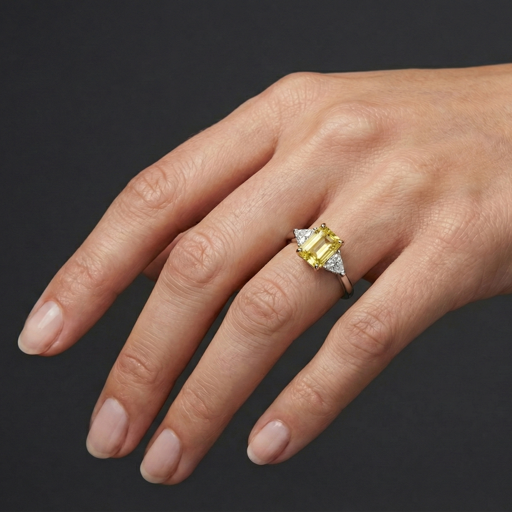 2.91 cttw Soleil Radiant-Cut Three-Stone Diamond Ring on hand. Featuring a 2.50ct IGI Certified Vivid Canary center and Trillion-Cut E-F/VS+ side stones in Solid 14K Gold with Insured Free Shipping.
