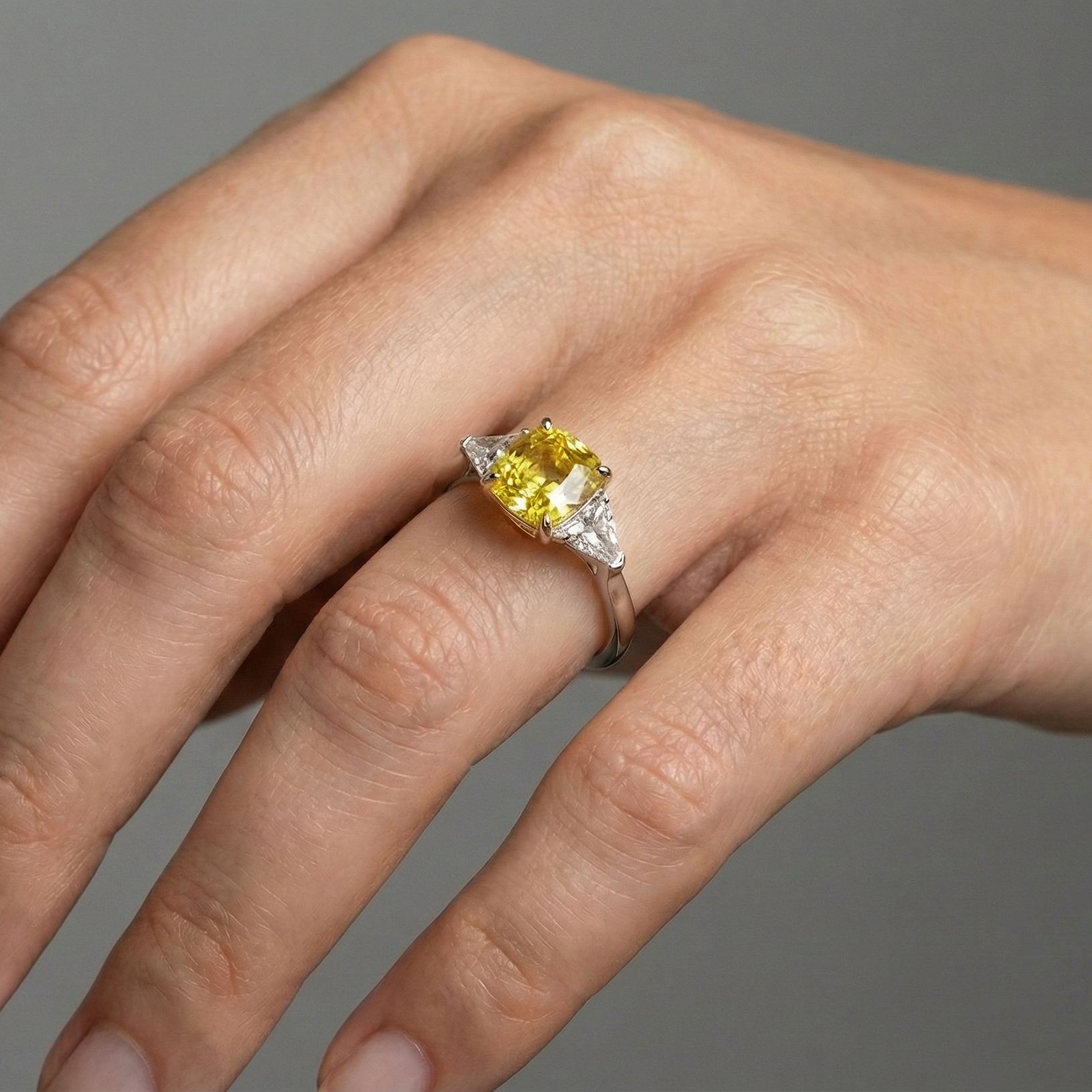 On hand view of the 4.16 Cttw Soleil Cushion Canary Trilogy Diamond Ring with 3.50ct IGI Certified Center Yellow Canary Cushion Stone and an additional .66 cttw Trillion Side Stones