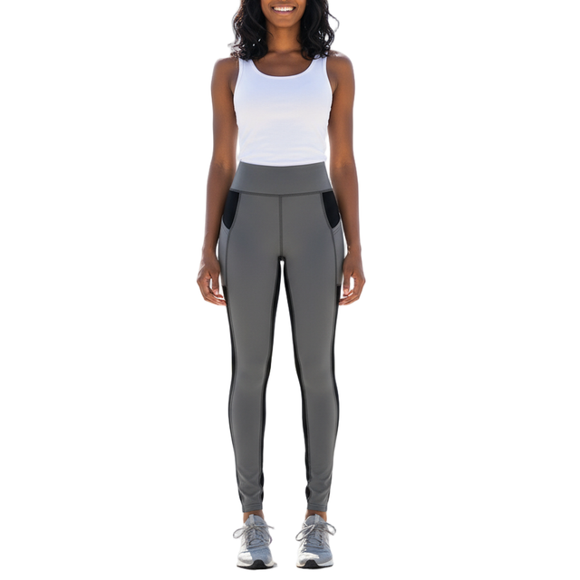 Woman wearing high-rise color block leggings with black slimming panels, grey  accents, and side pockets, standing in a sporty pose.