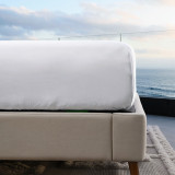 corner view of bed made with white resort sheets