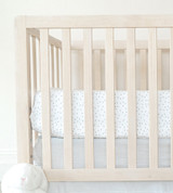 side of crib with showing mattress with dot dreamy white sheets on them