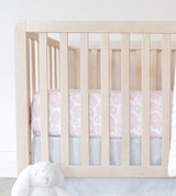 side of crib showing mattress with floral burst vintage blush sheets on them