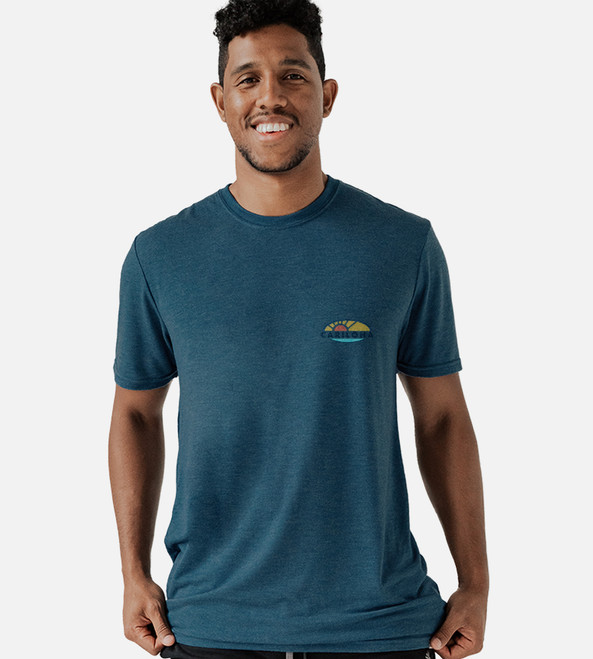 front view of model wearing bermuda blue crew tee with sunset & swells left chest graphic