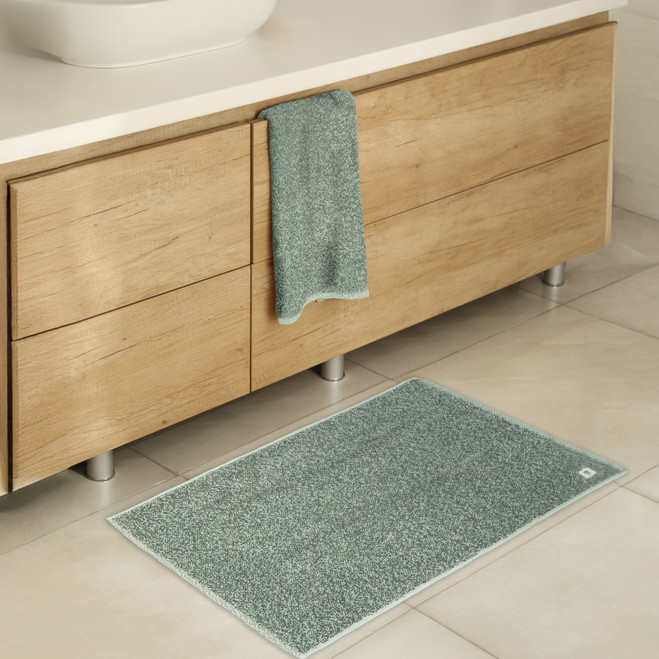 ocean green bath mat on the floor in a modern bathroom