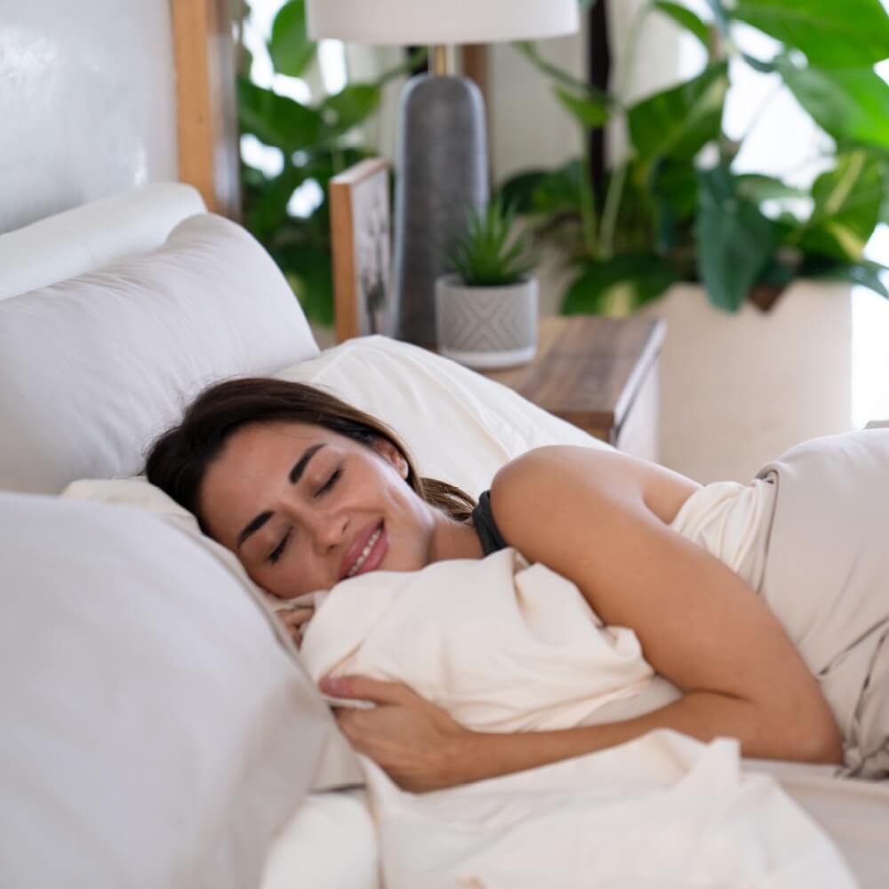Woman resting comfortably in bed, embracing soft Cariloha bamboo bedding