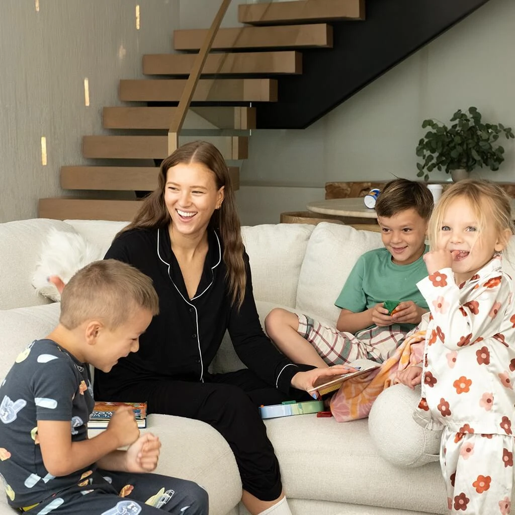 A mom wearing sleepwear helping he kids