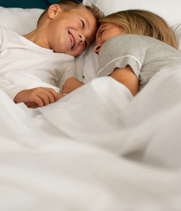 Mother and young son lying on Cariloha sheets