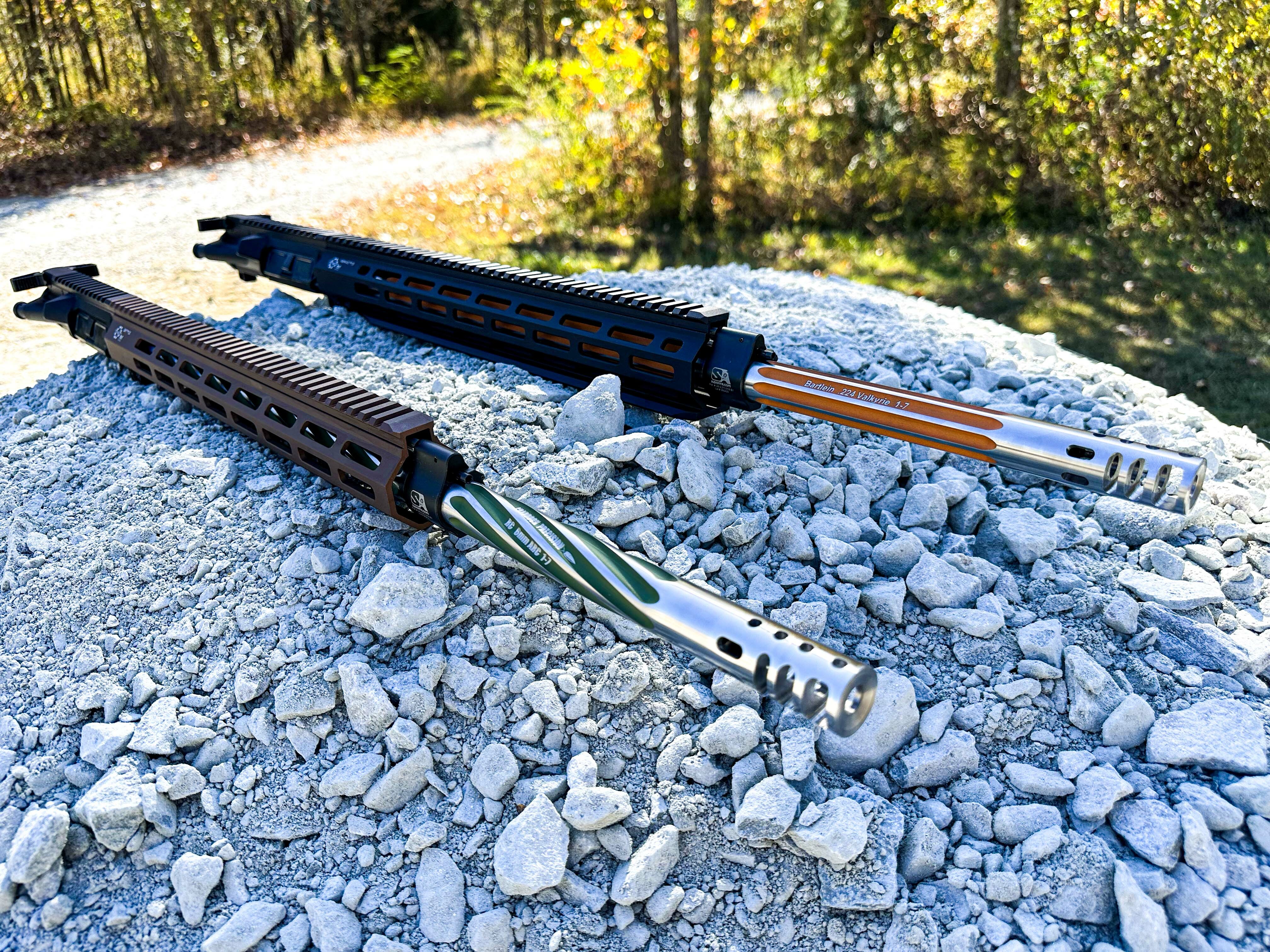 2 upper receivers laying on a bed of rocks