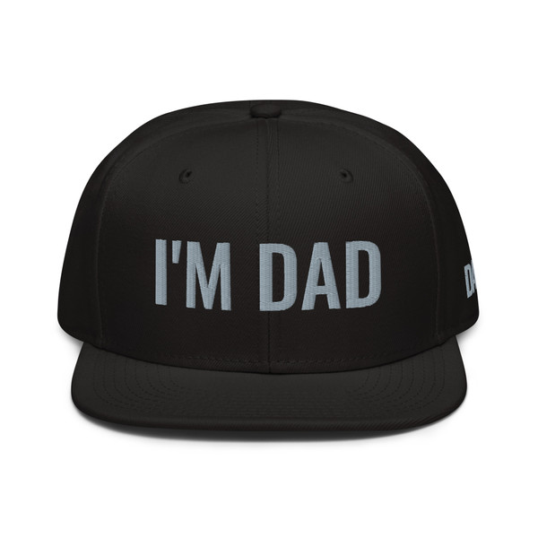 Black structured high-profile six-panel snapback hat with embroidered I'm DAD logo, front view — DAD all caps