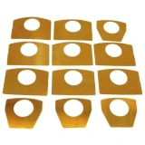 A set of ten yellowish-orange shim pieces for Allis-Chalmers farm tractor main bearing caps, with various hole and shape sizes.