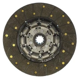 A large, circular, spring-loaded clutch disc with a metal center and a dark, textured friction surface. The surface is segmented and has multiple small yellow markings along the edge, indicating part details.