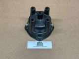 Distributor Cap ACR1954, a black automotive distributor cap with six ports for spark plug wires, displayed on a brown background with a label indicating it's a used part.