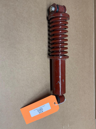 Allis Chalmers WD CA Seat Shock Absorber with Spring, red suspension shock with coil spring and mounting components for tractor seat, displayed on a brown background.