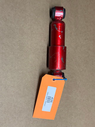 Tractor Seat Shock Absorber for Monroe Seat, display model, red metal suspension component with wear marks, attached to an orange tag labeled '436' for inventory or identification.
